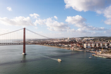 Boat crossing the 25 de abril bridge in Lisbon, Portugal.