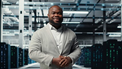Smiling manager in data center doing checkup on hardware to avoid downtime. Happy african american...