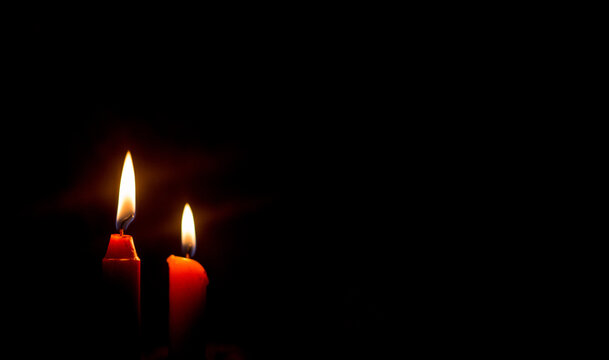 Dos velas rojas encendidas en fondo negro, iluminaci&oacute;n tenue y concepto de espiritualidad o reflexi&oacute;n