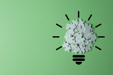 Light bulb made from a white puzzle on light green background with copyspace., Concept for...