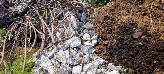 Construction Debris Scattered Across a Work Site With Soil and Vegetation in Background