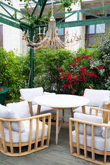 A cozy outdoor seating area with four rattan chairs and a round table surrounded by lush green...