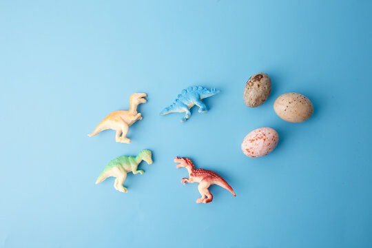 dinosaur toys in various poses on light blue surface for preschool education, creative visuals, toy shop promotions, children blogs, science-themed learning kits, digital content projects