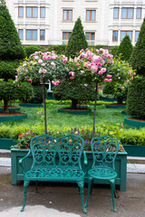 A modern outdoor seating area with green metal chairs and tables. lush greenery, recreation area.
