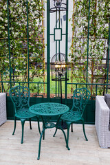 A modern outdoor seating area with green metal chairs and tables. lush greenery, recreation area.