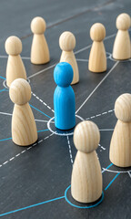 Obraz premium Blue Peg Leader: A single blue wooden peg stands out amidst a network of beige pegs, symbolizing leadership, connection, and influence in a team or organization.
