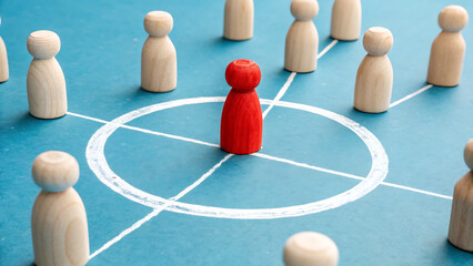 Obraz premium Leadership in Perspective: a red wooden figure stands out in a circle, surrounded by other wooden figures, symbolizing leadership, teamwork, and connectivity within a business, community or group.