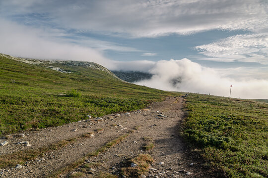 Mulen Mountain peak is shrouded in fog and clouds during a serene summer morning, creating a tranquil atmosphere in the nordic nature