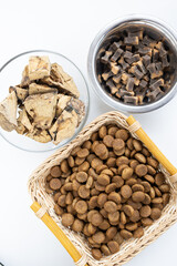 There are different kinds of pet treats in the bowl. Crispy breakfast cereals, chewing gums and pieces of dried meat. For the care of pets and their proper nutrition.