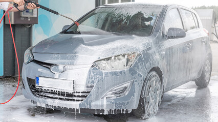 Man cleaning car. Spray hose foam soap. Car wash water shine exterior.