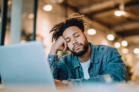 Tired man exhausted at his laptop needing a break from work