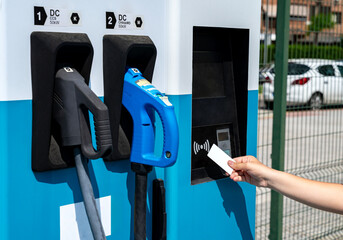 Driver paying with contactless card for electric vehicle charging at ev charger station.