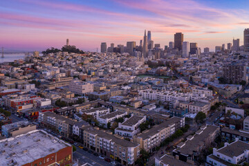 Aerial view of San Francisco, California, USA, at sunset. The city's skyline, including the Transamerica Pyramid and Coit Tower, is visible. The image captures the urban landscape.