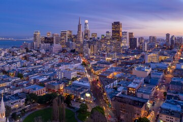 Obraz na płótnie Canvas San Francisco, USA, at dusk. Aerial view of the city skyline, including Coit Tower, the Bay Bridge, and illuminated skyscrapers, showcasing urban life.