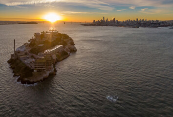 Alcatraz Island, a former prison, sits in the San Francisco Bay, USA, at sunset. The city skyline...