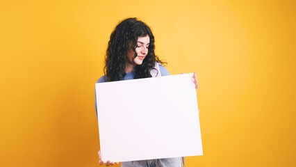 Young student woman showing blank whiteboard on yellow background