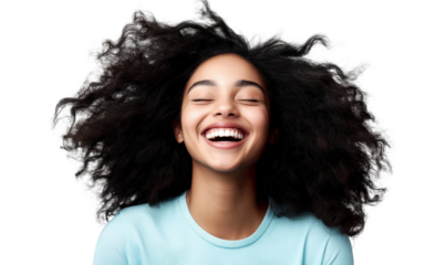 Joyful woman with voluminous curly hair laughing exuberantly in a bright, cheerful atmosphere, showcasing natural beauty and happiness with vibrant expression