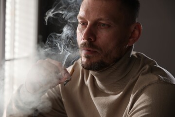 Man smoking cigarette near window in room