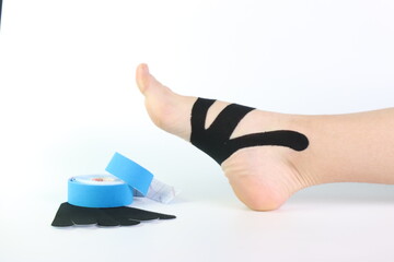 Woman foot with a kinesiology tape in black to recovery a foot sport pain