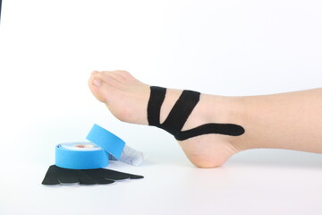 Woman foot with a kinesiology tape in black to recovery a foot sport pain