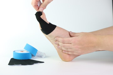 Woman foot with a kinesiology tape in black to recovery a foot sport pain