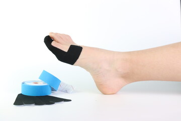 Woman foot with a kinesiology tape in black to recovery a foot sport pain