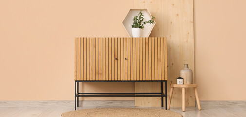 Interior of living room with wooden commode, stool and plant