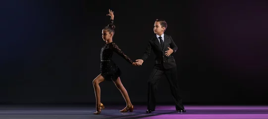 Poster Cute little children dancing against dark background