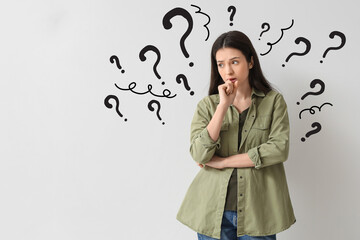 Portrait of worried young woman on  light background