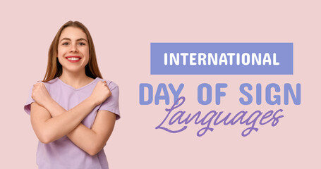 Young deaf mute woman using sign language on pink background
