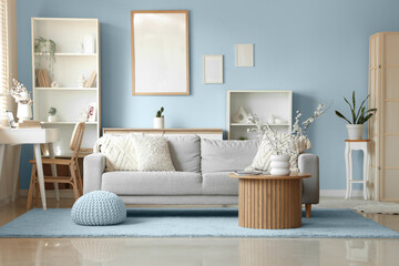 Interior of living room with sofa, shelving units and blooming branches in vases on coffee table