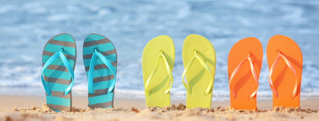 Set of beach flip-flops on sand near sea