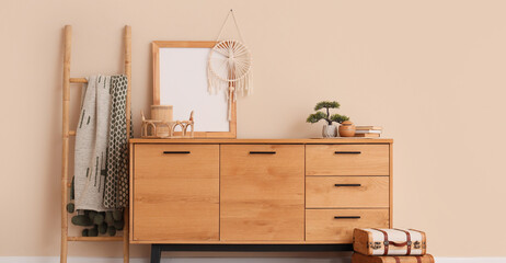 Interior of modern room with stylish dresser and ladder near beige wall