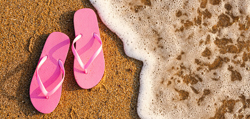 Stylish flips flops on sand near ocean at resort