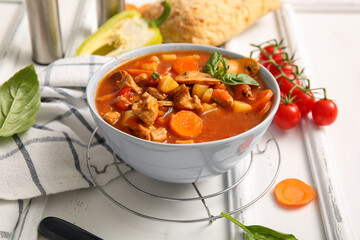 Bowl of tasty beef stew on white wooden background