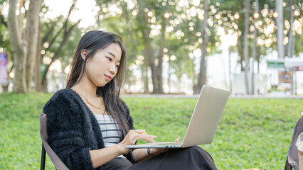 Young woman sitting on park with using laptop