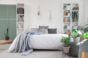 Interior of modern bedroom with shelving units and houseplants