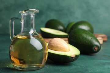 Jug of avocado oil on green background