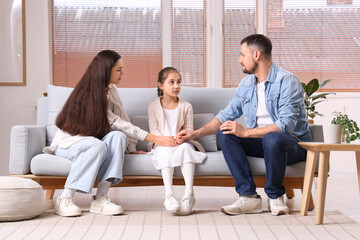 Parents apologizing to their daughter on sofa at home
