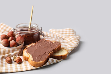 Bread slices with sweet chocolate spread and hazelnuts on grey background