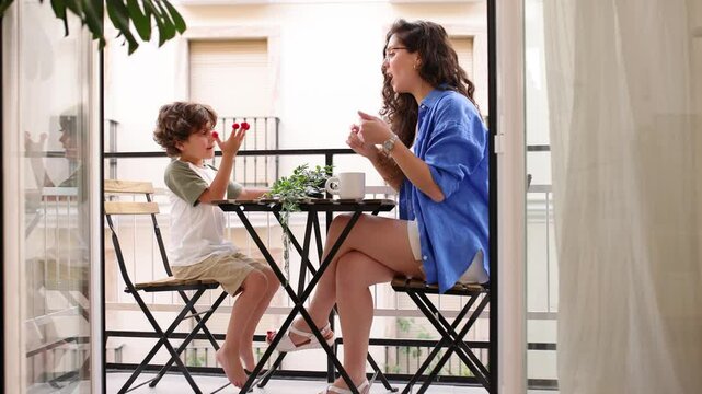 Cheerful young mother and son sitting in balcony
