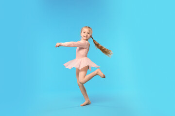 Naklejka premium Cute little girl dancing on light blue background