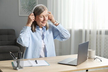 Smiling woman learning online using laptop at table indoors. Self-study