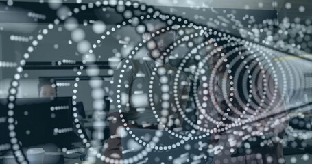 Collaborating project team wearing blazers around table in office, with laptops and coffee cup