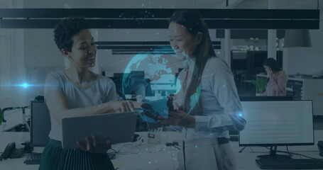 Discussing project details women in corporate attire using laptop and smartphone in office