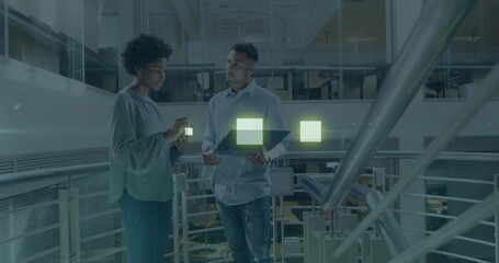 Discussing tech professionals analyzing data projections on mezzanine railing, with laptop and cube