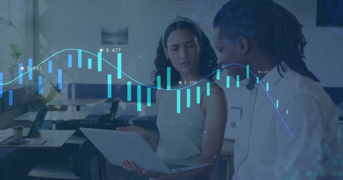 Analyzing data coworkers in business attire reviewing laptop at open-plan office, with data overlay