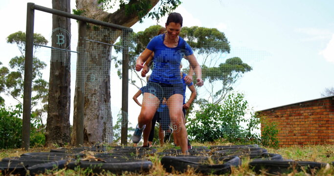 Fitness classmates stepping through tire grid in park, wearing athletic shirts and shorts