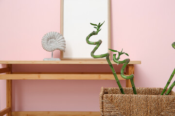 Interior of stylish room with wooden table and bamboo stems in wicker basket