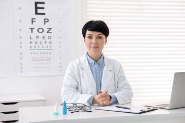 Portrait of professional ophthalmologist at white table in clinic